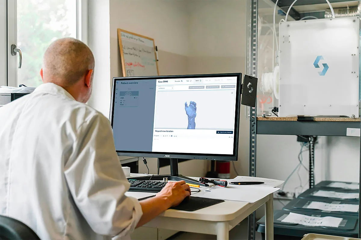 Designer refining a 3D CAD model on screen next to the hand sketch it was built from