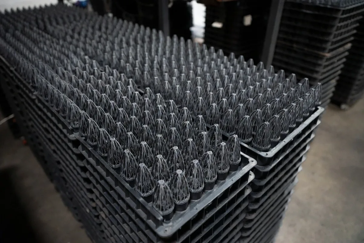 Hundreds of identical 3D printed production parts arranged in rows for quality inspection